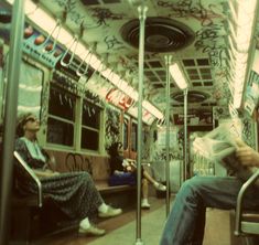 two people sitting on a subway car with graffiti all over the walls and flooring