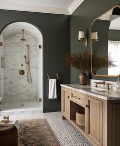 a bathroom with green walls and marble counter tops, gold fixtures and an arched shower