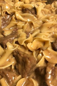 some noodles and meat are being cooked in a skillet on the stove with brown gravy