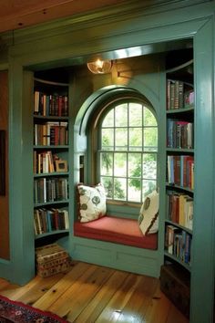 a window seat in the corner of a room with bookshelves