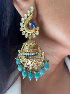 Discover the beauty of these traditional gold-plated Kundan jhumkis, featuring intricate designs and elegant peacock motifs. Adorned with mint green bead drops, these jhumkas add a touch of elegance to any outfit. Perfect for festive occasions or special events, these earrings beautifully blend traditional craftsmanship with modern style. Earrings are Approximately 3.6 inches Long and 1 inch Wide  Our products are meticulously handcrafted, ensuring each piece is unique. Due to the manual craftsm Earrings Kundan, Peacock Motifs, Princeton Nj, Green Pearls, Peacock Design, Intricate Designs, Style Earrings, Green Bead, Pearl Drop