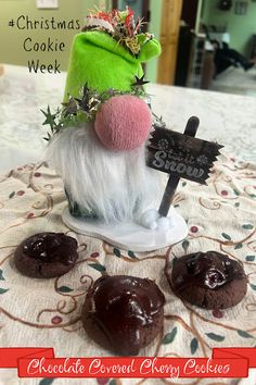 a table topped with chocolate covered donuts and a green santa hat on top of it