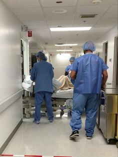 three doctors in scrubs walking down a hospital hallway