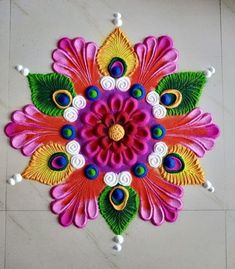 a colorful flower design on the floor with green leaves and white balls around it's center