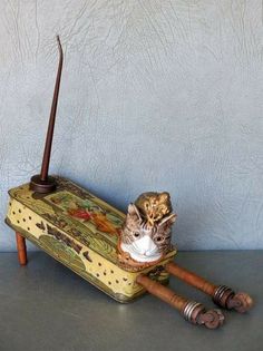 a cat sitting on top of a suitcase next to an old fashioned toothbrush holder