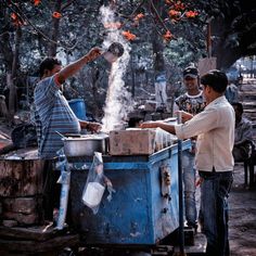 two men are cooking food on an outdoor grill