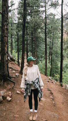 a woman walking down a trail in the woods