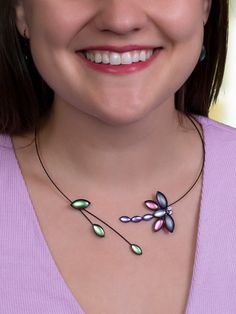 a close up of a woman wearing a necklace with flowers on the front and side