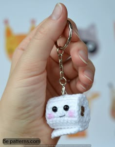 a hand holding a keychain with a small toy in the shape of a marshmallow