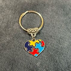 a heart shaped puzzle piece keychain on top of a gray carpeted floor