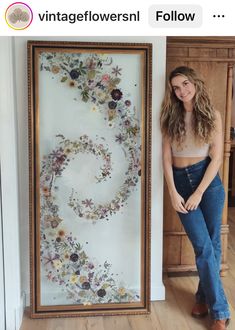 a woman standing in front of a painting with flowers on it