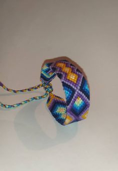 a close up of a colorful bracelet on a white surface with a blue and yellow bead design