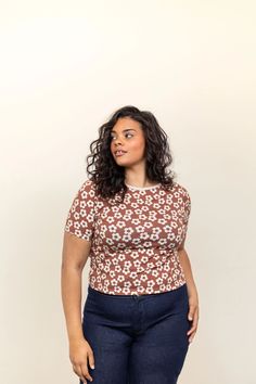 a woman standing in front of a white wall with her hands on her hips and looking off to the side