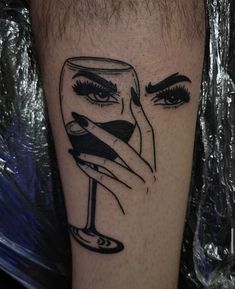 a woman holding a wine glass with her face painted on the side of her leg