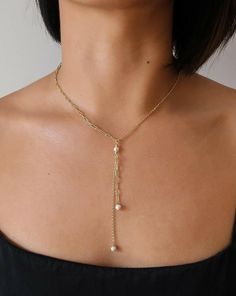 This Pearl and Gold Lariat Necklace is calling your name. Half of this Italian gold Y necklace features a modern paperclip style while the other half features a rolo chain -- all dripping with beautiful freshwater pearls to take it to the next level. Perfect for layering with other necklaces to create a stunning ensemble or leaving alone as a statement piece. Adjustable from 16 to 18 inches for the perfect fit. Details: Metal: 14kt 1-Micron Gold-Plated on Sterling Silver Base Material: Freshwater Pearl Pearl Size: 5mm pearls Length: 16-18" Adjustable Chain Elegant Lariat Necklace With Paperclip Chain, White Lariat Necklace With Chain Detail, White Lariat Necklace With Chain, White Lariat Necklace, Minimalist Pearl Chain Lariat Necklace With Dangle, Chic Gold Lariat Necklace With Pearl Chain, Gold Lariat Necklace, Y Necklace, The Other Half