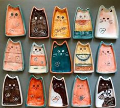 nine ceramic cats are sitting in rows on the table, each painted with different colors