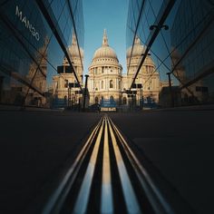 an image of a city street with buildings in the back ground and shadows on the sidewalk