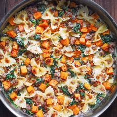 a pan filled with pasta and vegetables on top of a wooden table