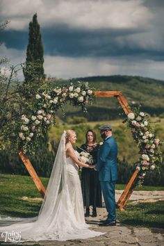 a bride and groom standing in front of an arch with flowers on it at the end of their wedding ceremony