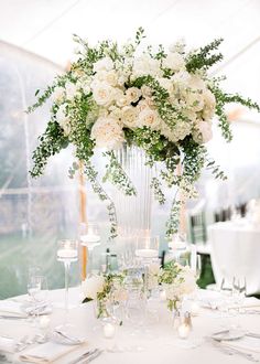 an elegant centerpiece with white flowers and greenery