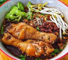 a bowl filled with meat and vegetables on top of a wooden table