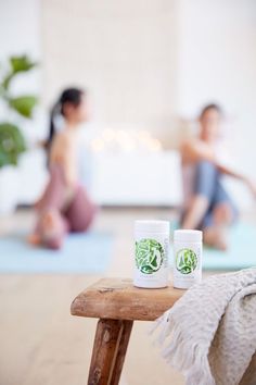 two white cups sitting on top of a wooden table next to a woman in the background