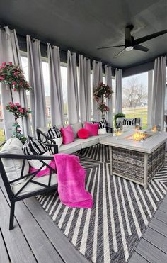 an outdoor living room with large windows and striped rugs on the floor, along with black and white furniture