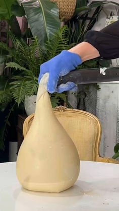 a person in blue gloves is making a vase