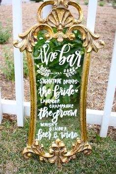 a gold framed mirror sitting on top of a grass covered ground next to a white picket fence