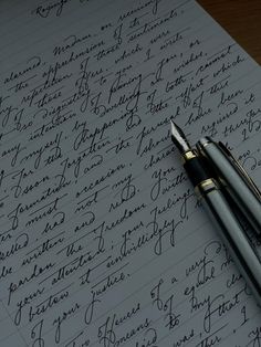 two fountain pens sitting on top of a piece of paper with cursive writing