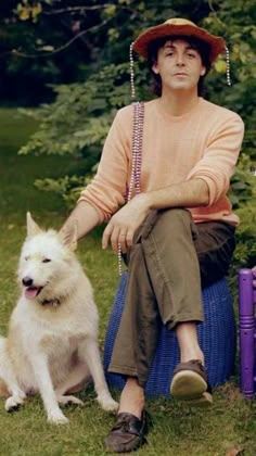 a man sitting on top of a blue barrel next to a white dog