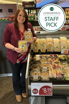 a woman standing in front of a display case filled with food