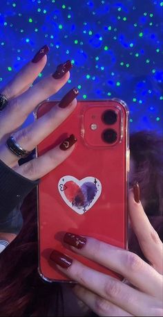 a woman holding up her red phone case with heart stickers on the front and sides