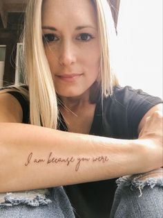 a woman with a tattoo that says i am because you were on the arm and behind her