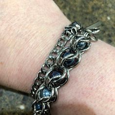 a close up of a person's arm wearing a silver bracelet with blue stones