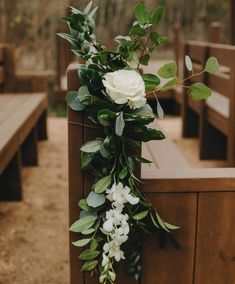 white flowers and greenery are on the back of pews