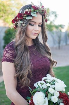 a woman holding a bouquet of flowers in her hand and wearing a flower crown on her head