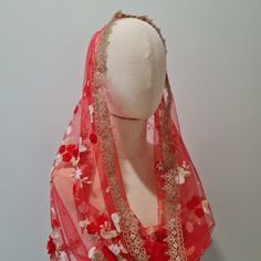 a mannequin wearing a red veil with flowers on it