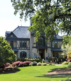 a large house sitting on top of a lush green field next to trees and bushes