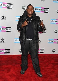 a man standing on top of a red carpet in front of an american music awards