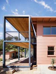 a pink house with a wooden roof and metal balconies on the front porch