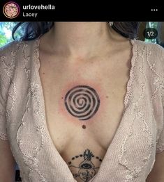 a woman's chest with a tattoo on it that looks like a spiral design