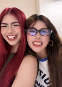 two girls with red hair and glasses are smiling