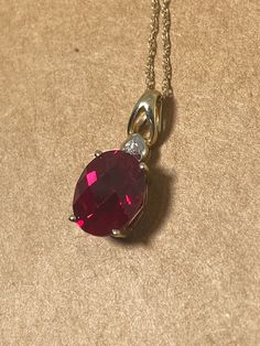 Featuring a large oval faceted synthetic ruby measuring 10mm x 8mm approx.  4-claw set,  topped by round diamond  crafted in 9K yellow gold  Pendant's height: 20mm  On a delicate 10K yellow gold chain,  44.5cm long  completed by ring spring clasp  Total item's weight: 1.8gr. Classic Ruby Round Pendant Jewelry, Classic Round Ruby Pendant Jewelry, Classic Necklace With Lab-created Ruby, Classic Red Oval Pendant Jewelry, Classic Ruby Jewelry With Round Stone, Classic Round Ruby Jewelry, Classic Round Necklace With Lab-created Ruby, Red Oval Cubic Zirconia Jewelry, Classic Round Lab-created Ruby Necklaces