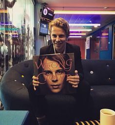 a man sitting on a couch holding up a poster