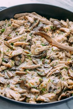 a skillet filled with mushrooms and parsley on top of a marble countertop