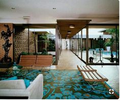 a living room filled with furniture next to a swimming pool on top of a wooden floor