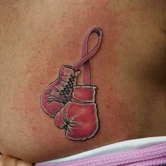 a woman's stomach with a pink ribbon and boxing gloves tattoo on her belly