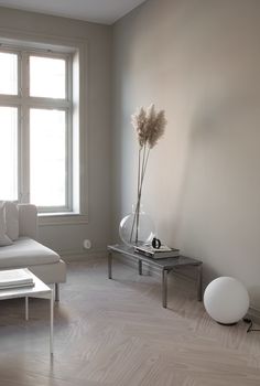 a living room filled with furniture and a white couch next to a large window on top of a hard wood floor