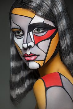 a woman with painted face and body is posing for the camera while she has her hair pulled back